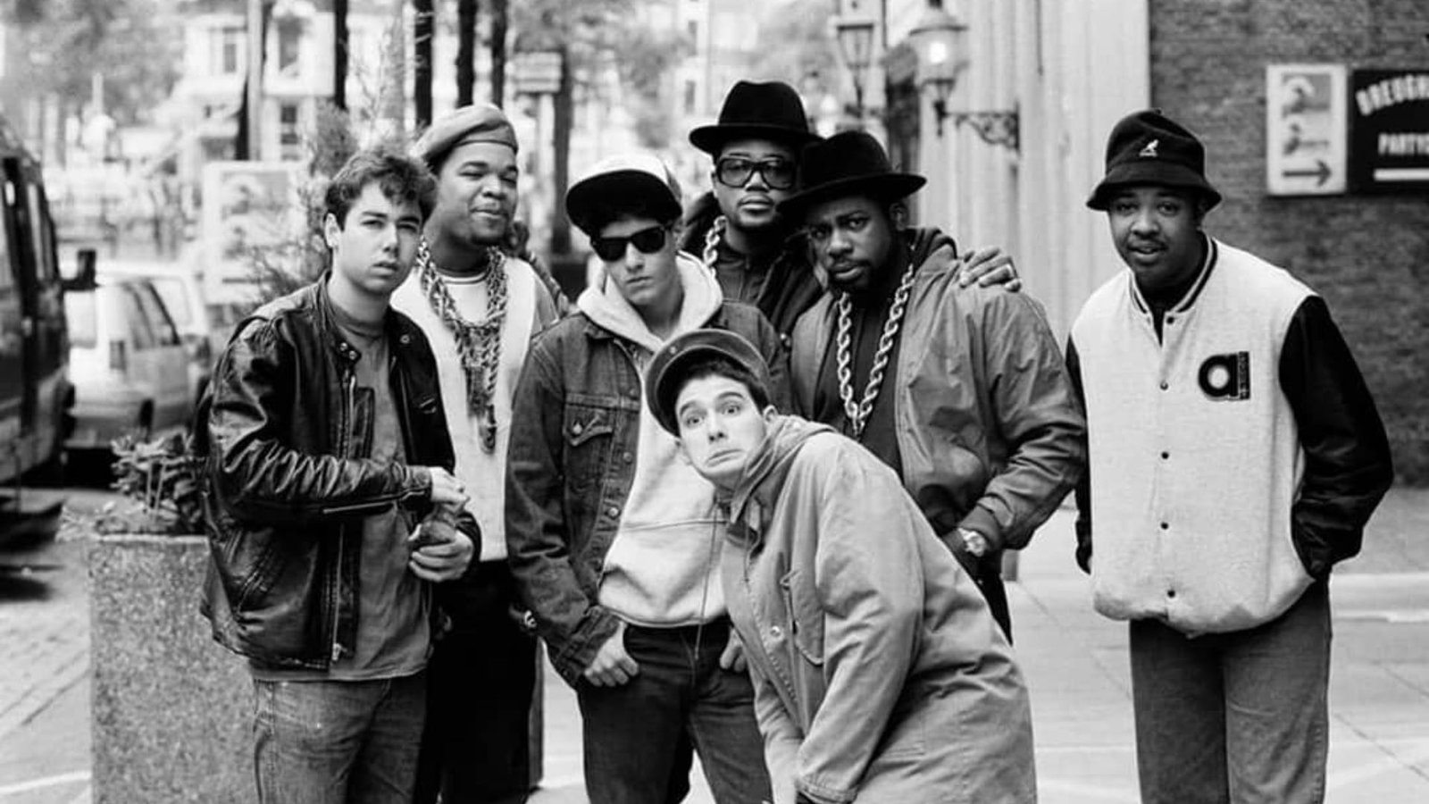 A group of young men standing together on a city street, engaged in conversation.