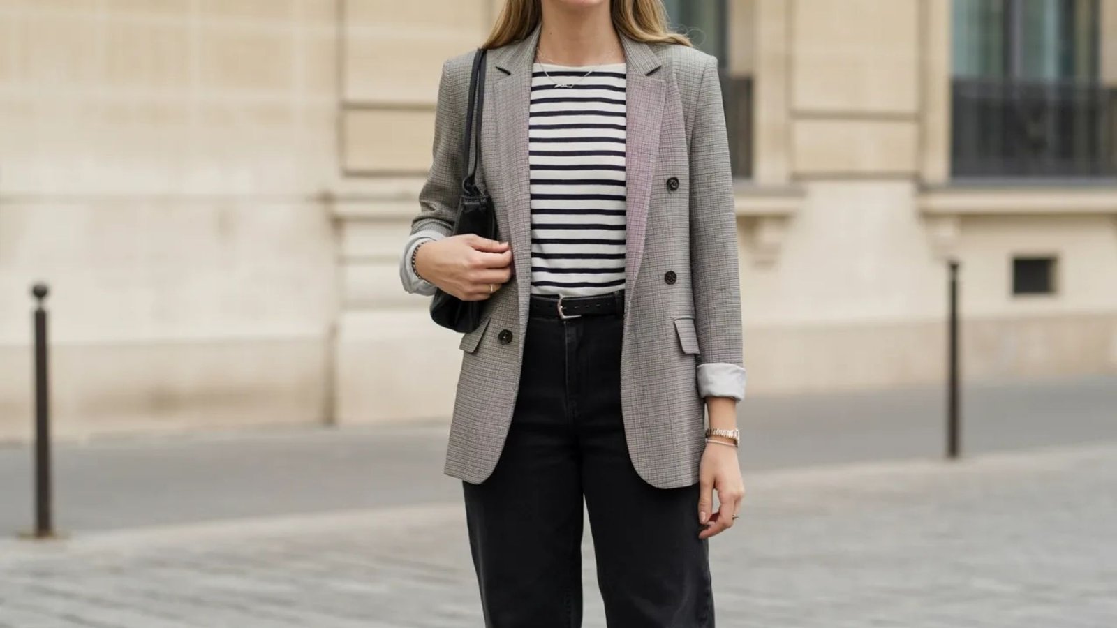 A woman in a striped shirt and blazer stands confidently, showcasing a stylish and professional appearance.
