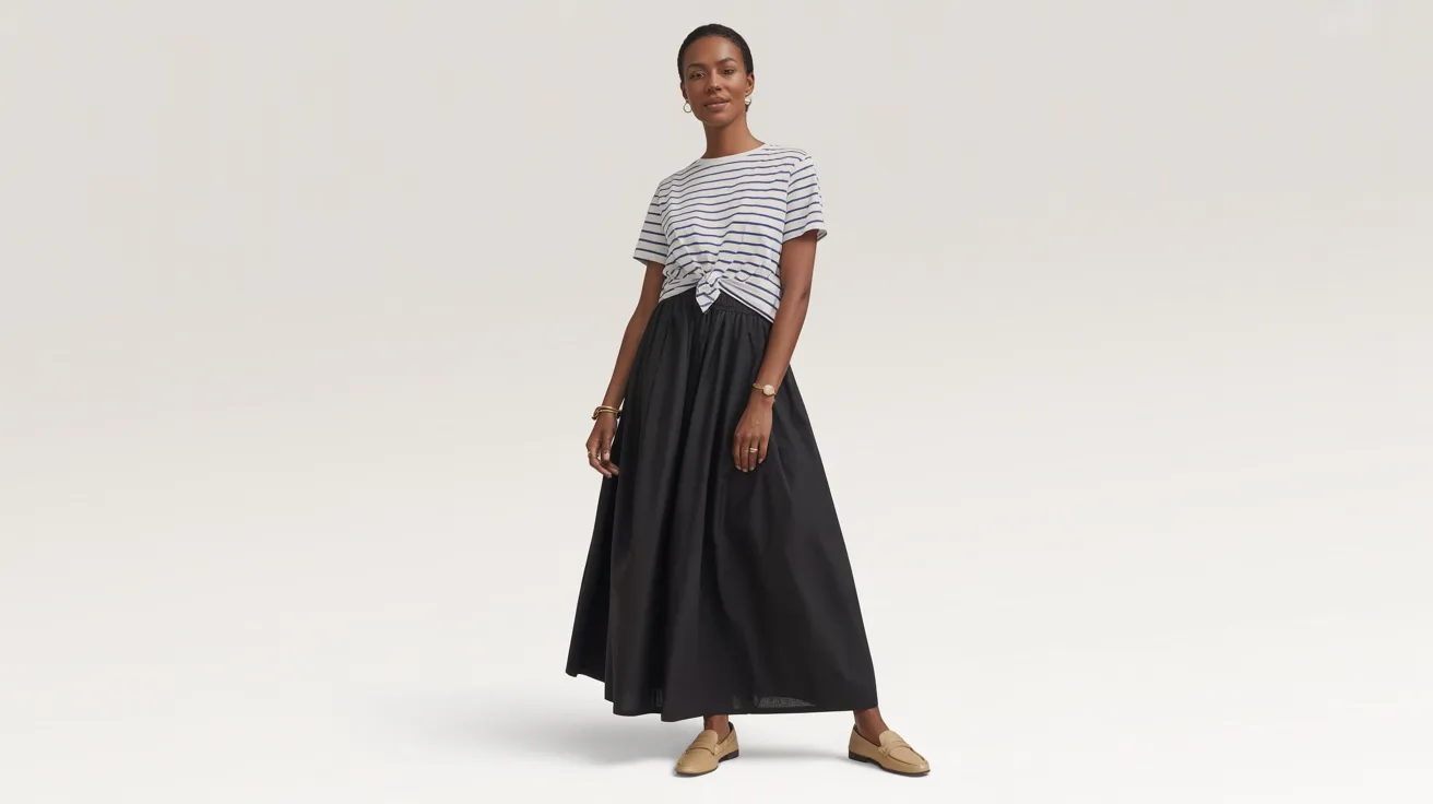 A woman wearing a striped shirt and a black skirt stands confidently, showcasing her stylish outfit.