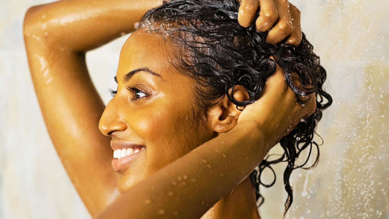 A woman washes her hair in the shower, preparing for Senegalese twists with curls as part of her hair care routine.