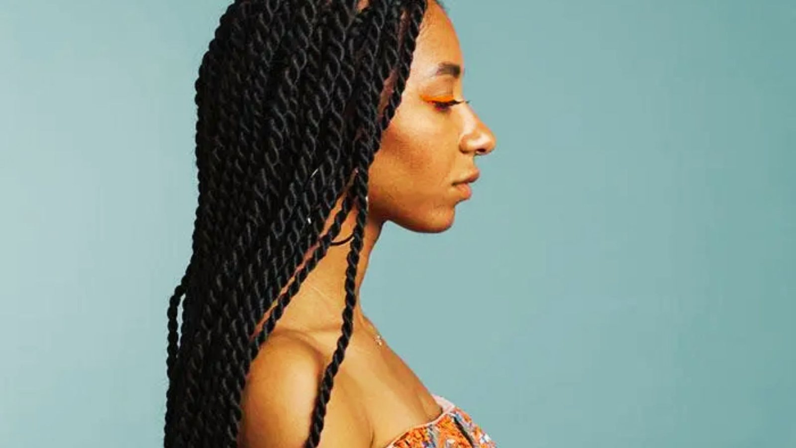 A woman with long braids styled neatly, showcasing the final touches of her Senegalese twists with curls.