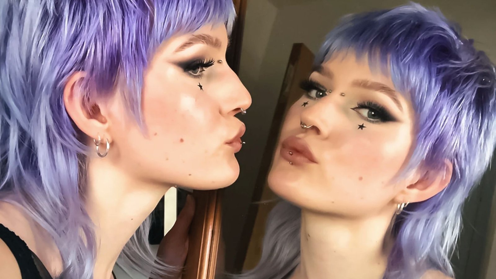 A woman with a modern mullet haircut and purple hair gazes into a mirror, reflecting her perfect style.