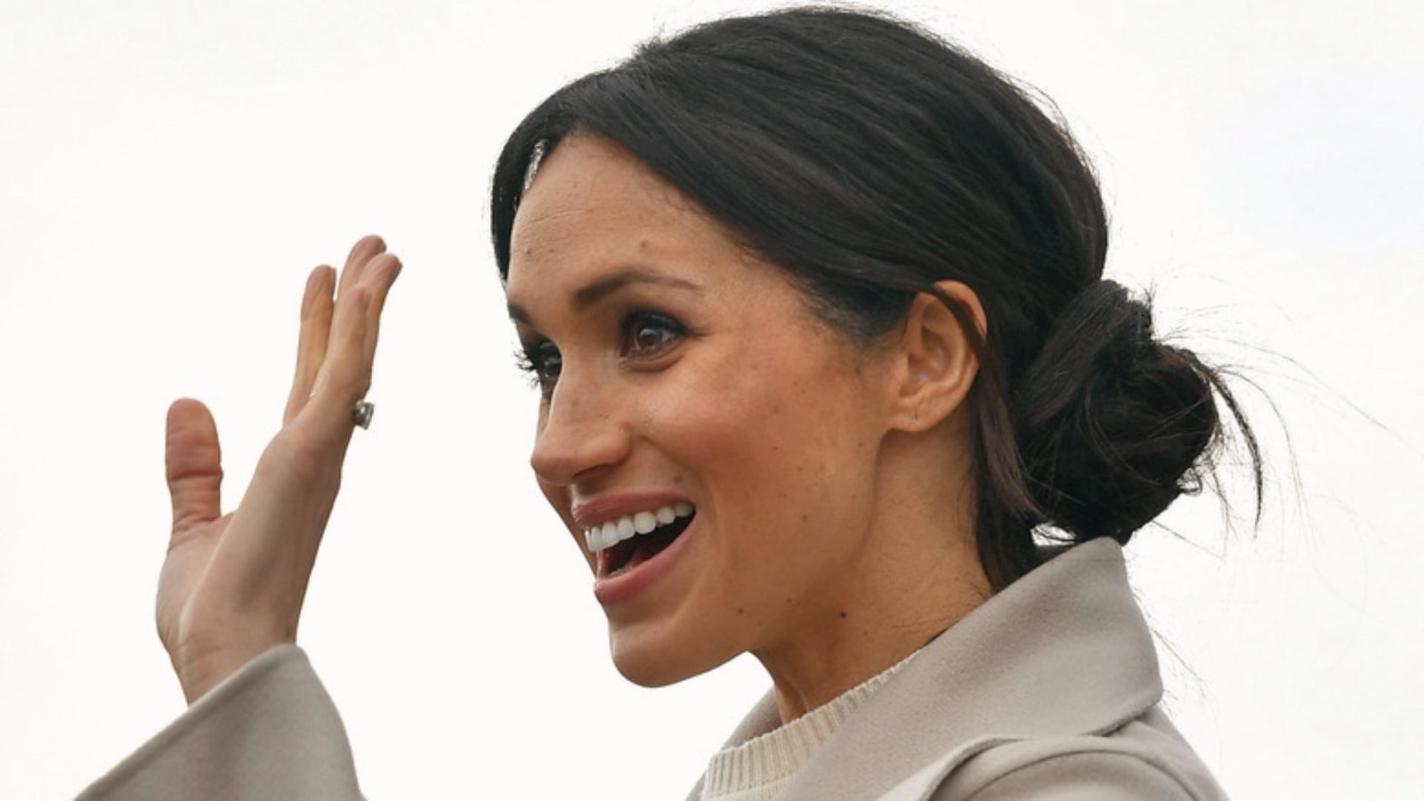 A lady with her low loose messy bun and wispy bangs framing her smiling face.