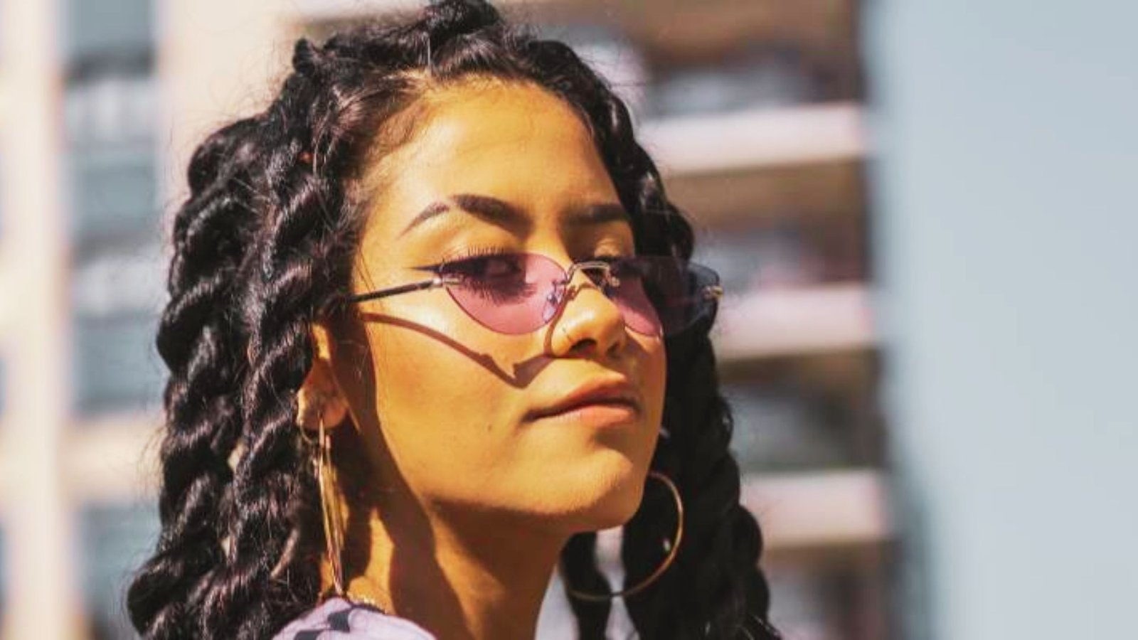 A woman with long braids and sunglasses, showcasing styling ideas for Senegalese twists with curls.