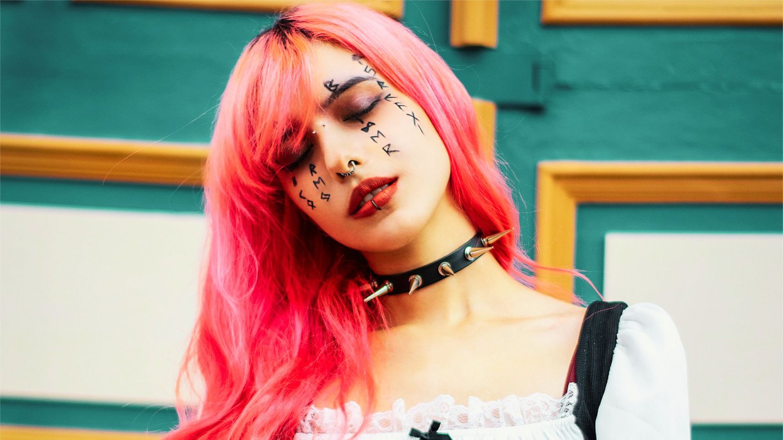 A woman with pink hair wears a black and white dress, embodying the pastel goth aesthetic with a blend of dark and soft themes.
