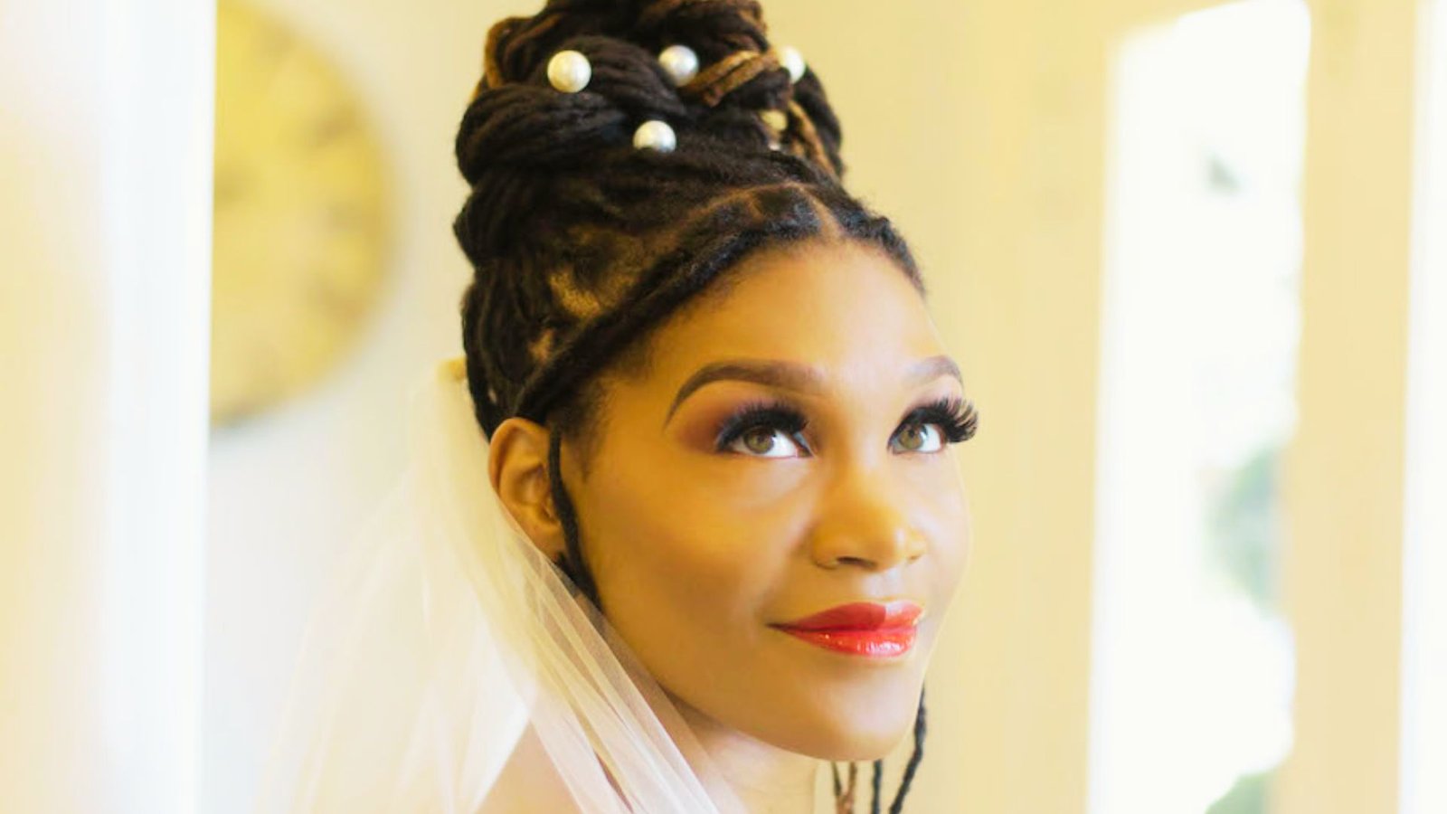 A woman with dreadlocks wearing a white dress, showcasing a proper faux locs wedding hairstyle.