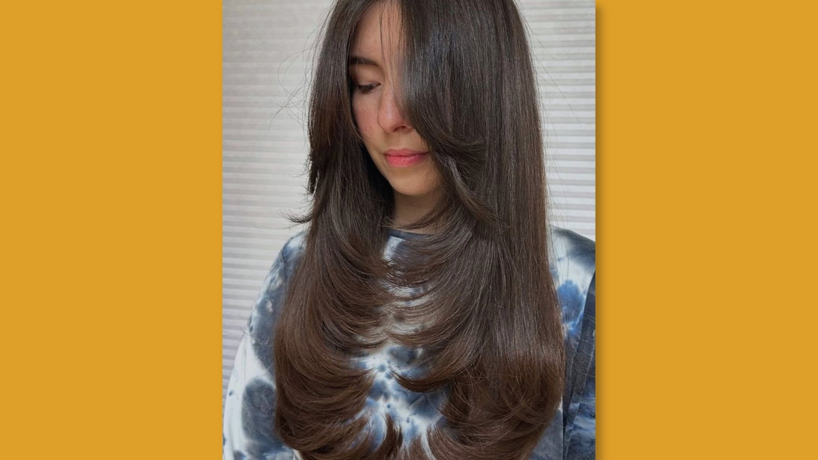 Low maintenance medium length layered hairstyle with face-framing curtain bangs on smooth dark brown hair for round face
