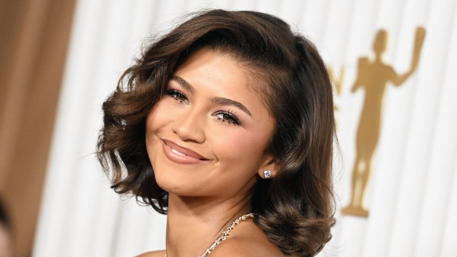 A woman with a platinum butterfly cut hairstyle wearing a necklace, showcasing her stylish look.
