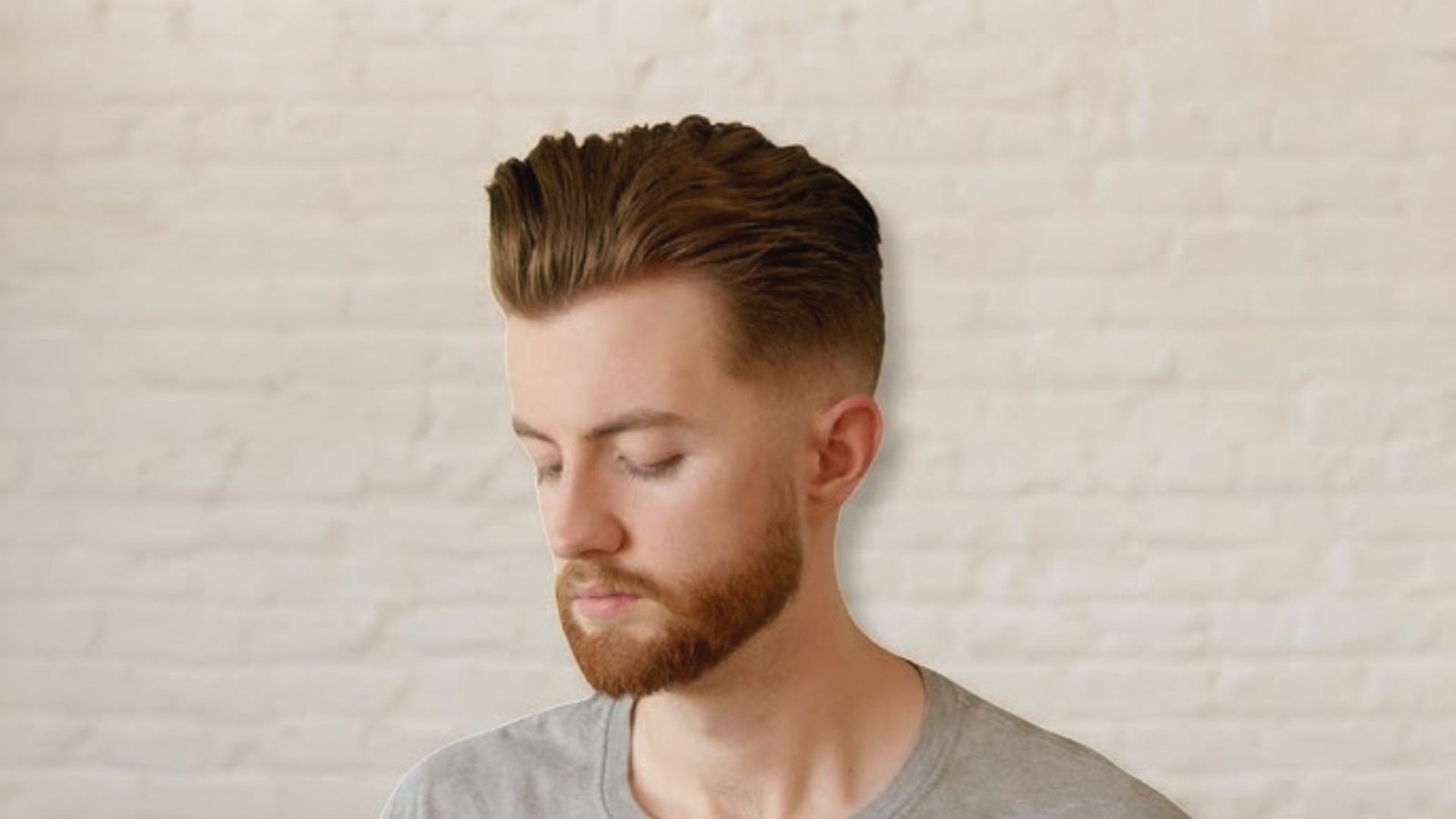 A man with a beard and a short haircut featuring a brush back disconnected undercut fade.