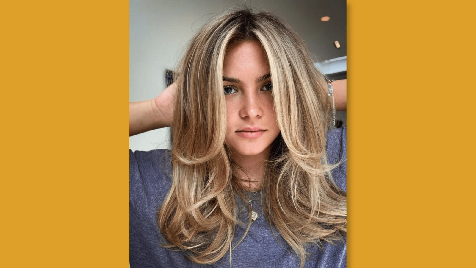 Low maintenance voluminous medium length layered haircut with curtain bangs and bouncy face-framing layers on blonde highlighted hair for round face 
