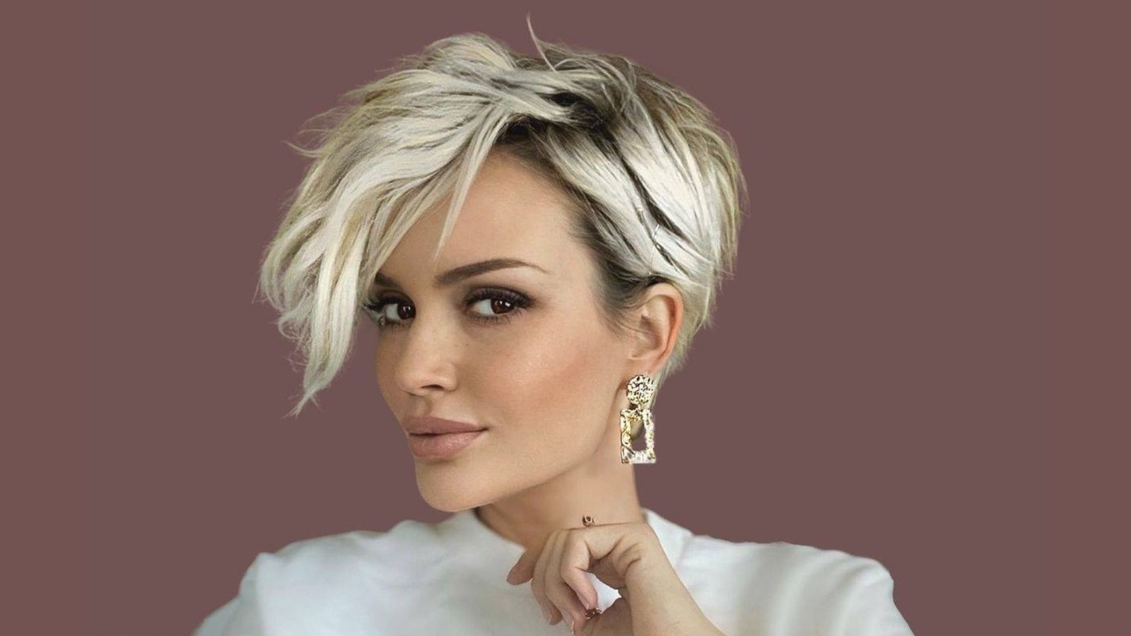 Woman with an icy blonde asymmetrical undercut pixie and deep side part.
A long textured top sweeps across while the opposite side is shaved close to the scalp.