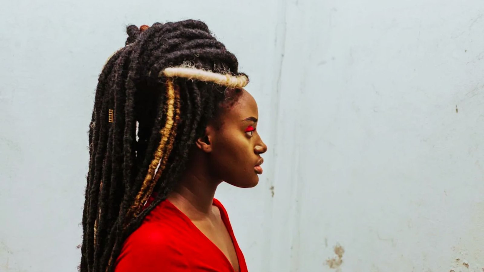 A woman with layered faux locs wearing a vibrant red dress, showcasing a stylish and bold hair ideas.