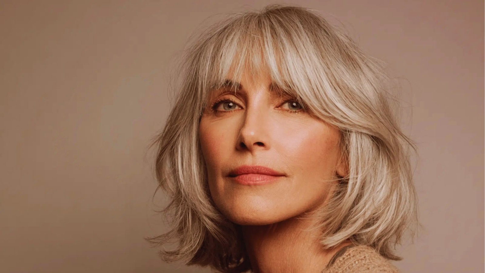 Shoulder length shag haircut with wispy curtain bangs and textured layers on silver blonde hair