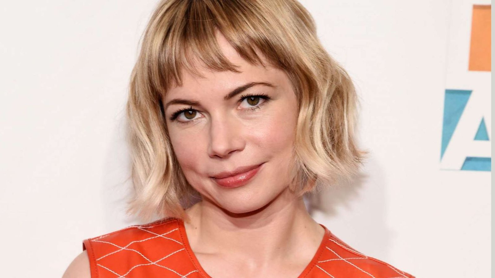 Woman with a blonde wavy bob and piecey micro bangs. The choppy, eyebrow-grazing fringe has uneven texture and soft separation.