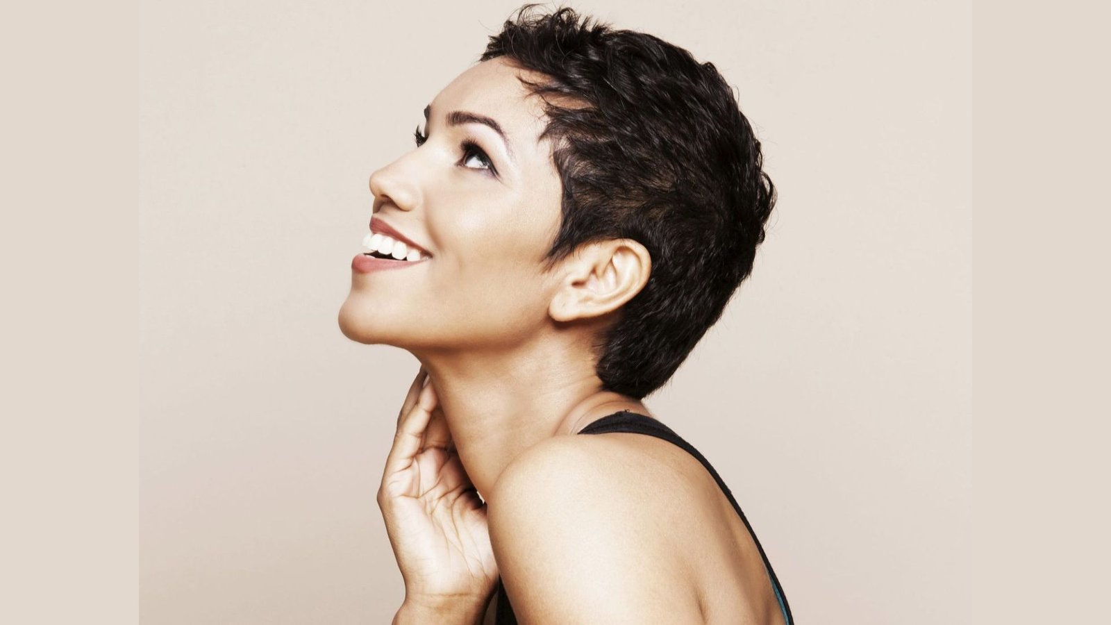Profile of a smiling woman with a dark curly pixie undercut and tapered sides.