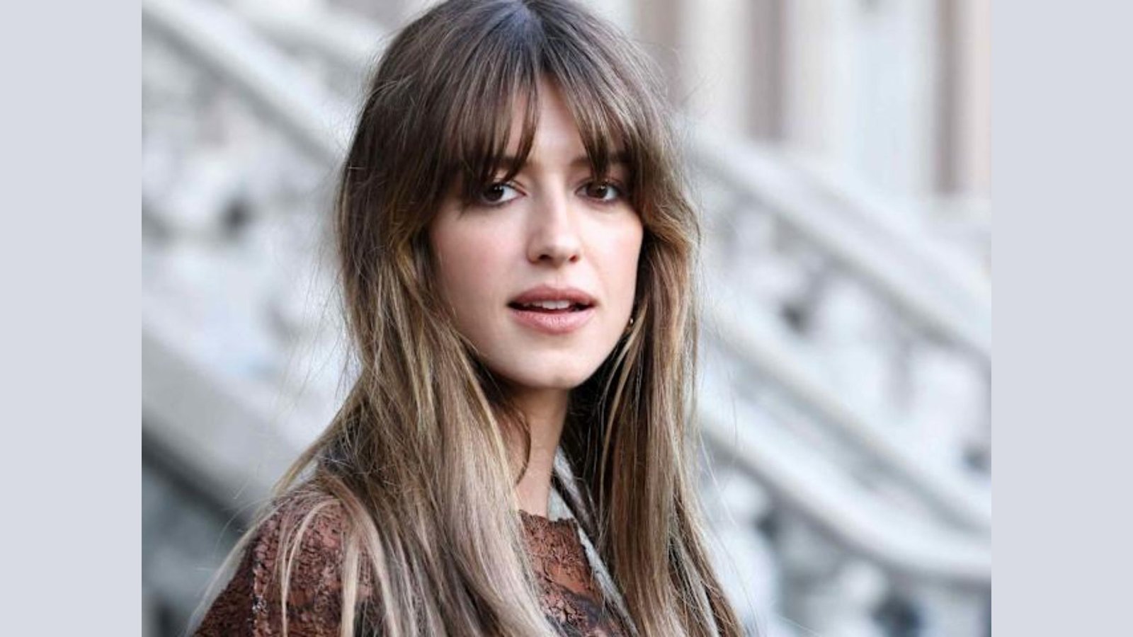 Woman with long, straight highlighted hair and soft French-girl bangs.
The wispy, brow-grazing fringe is slightly parted in the center and blends into long layers.