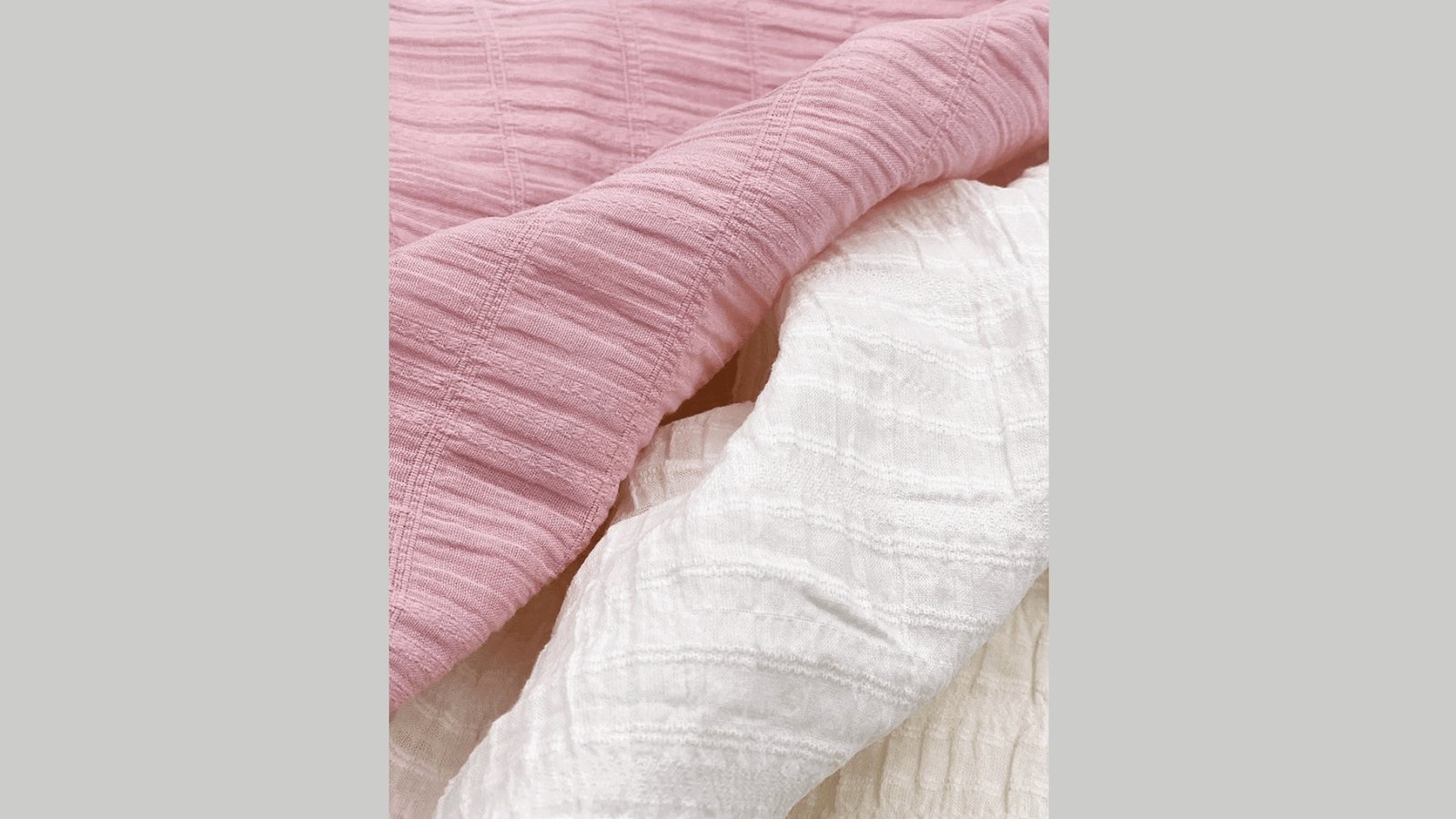 Pink and white textured fabric, soft and crinkled, layered together. The image conveys a sense of comfort and simplicity.