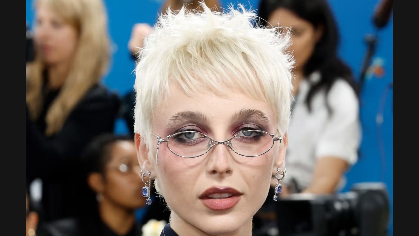 Close-up of a woman with a platinum blonde textured pixie undercut and wispy bangs.