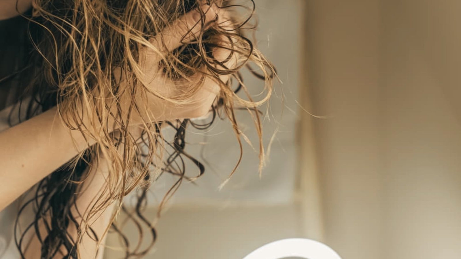 A woman is applying products and scrunching for a voluminous look.