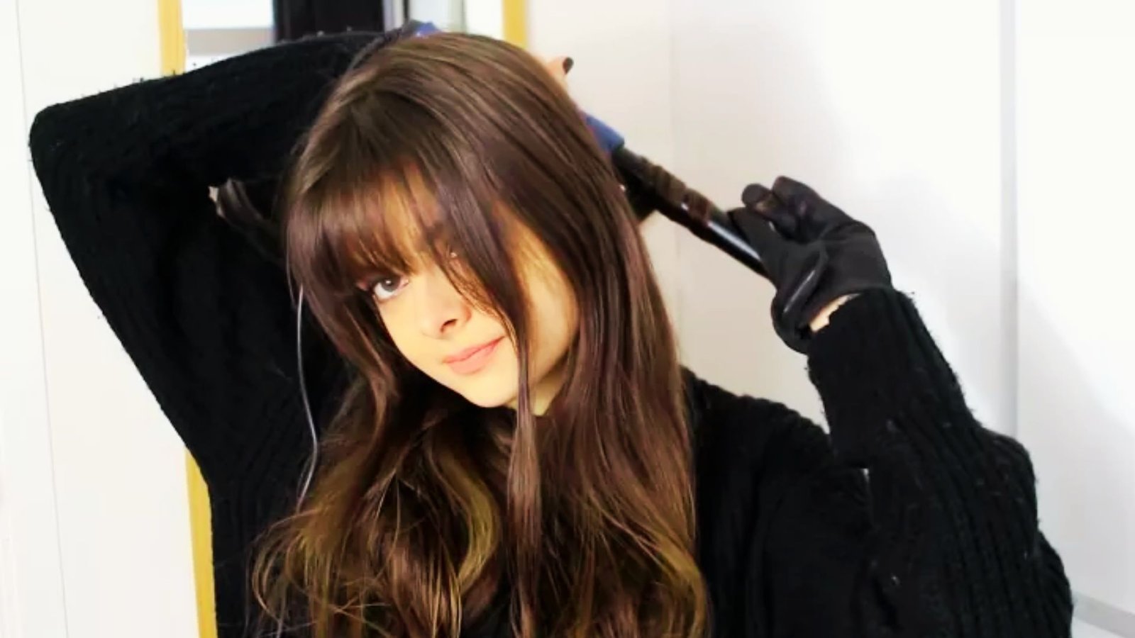 A woman with long hair brushing her hair, demonstrating the air-dry method for styling Bardot bangs at home.
