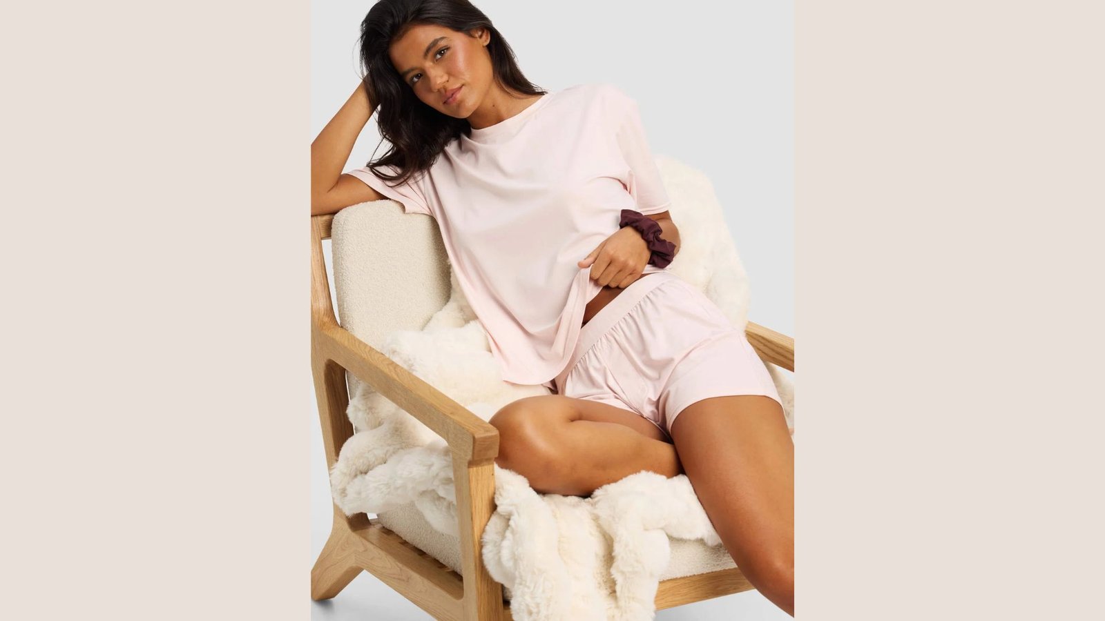 Woman wearing a soft light pink tee and matching shorts sitting on a fuzzy chair. Cozy stay at home mom outfit for everyday comfort while relaxing or lounging.
