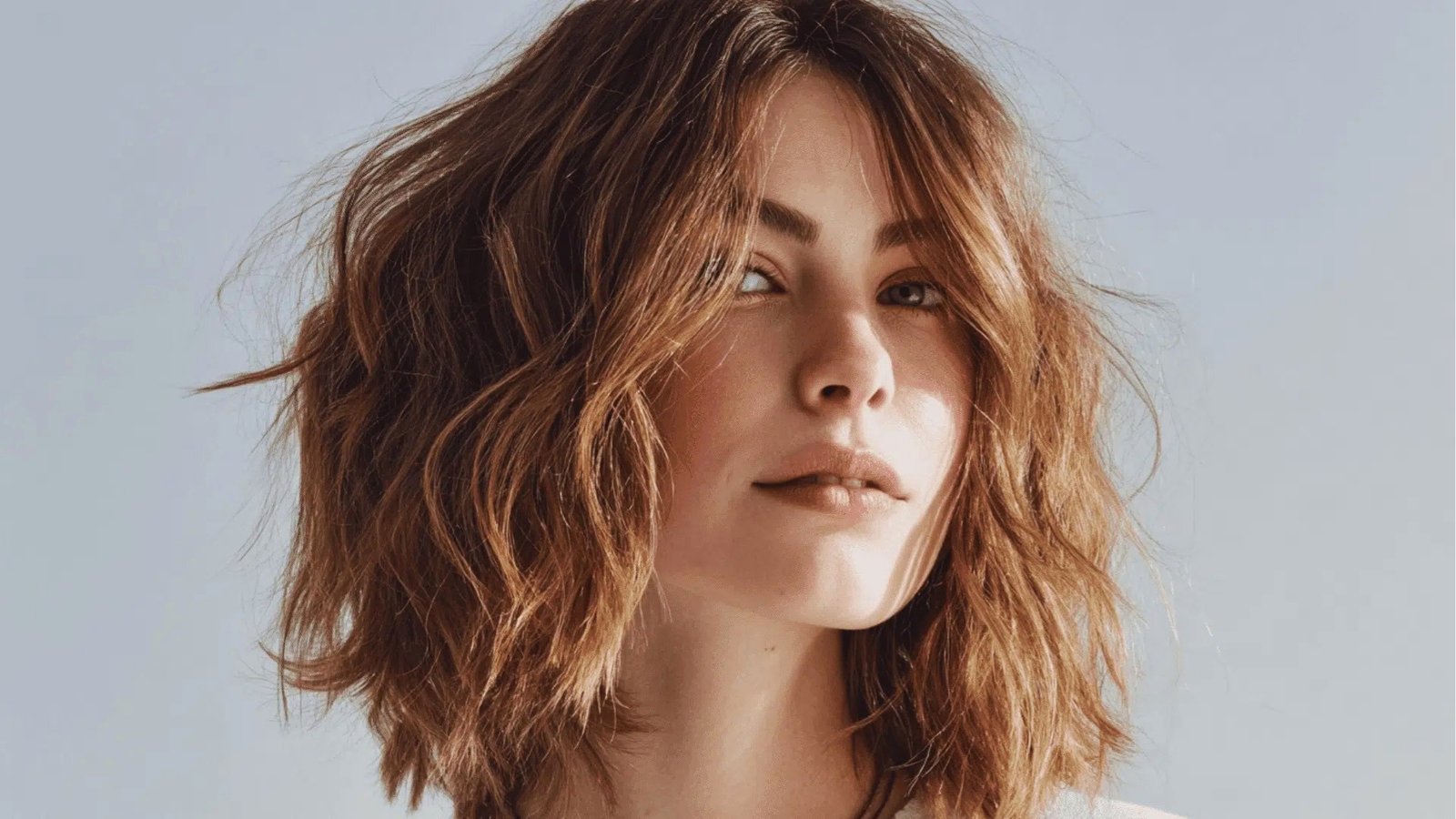 Tousled auburn shoulder length shag haircut with choppy layers and soft curtain bangs