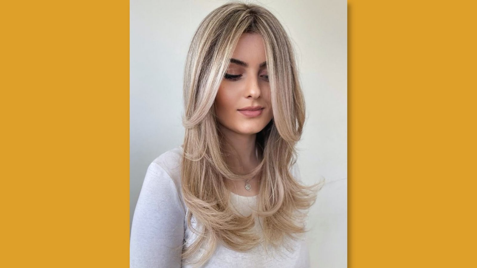 Low maintenance medium length layered hairstyle with soft curtain bangs and bouncy layers on blonde balayage hair for round face
