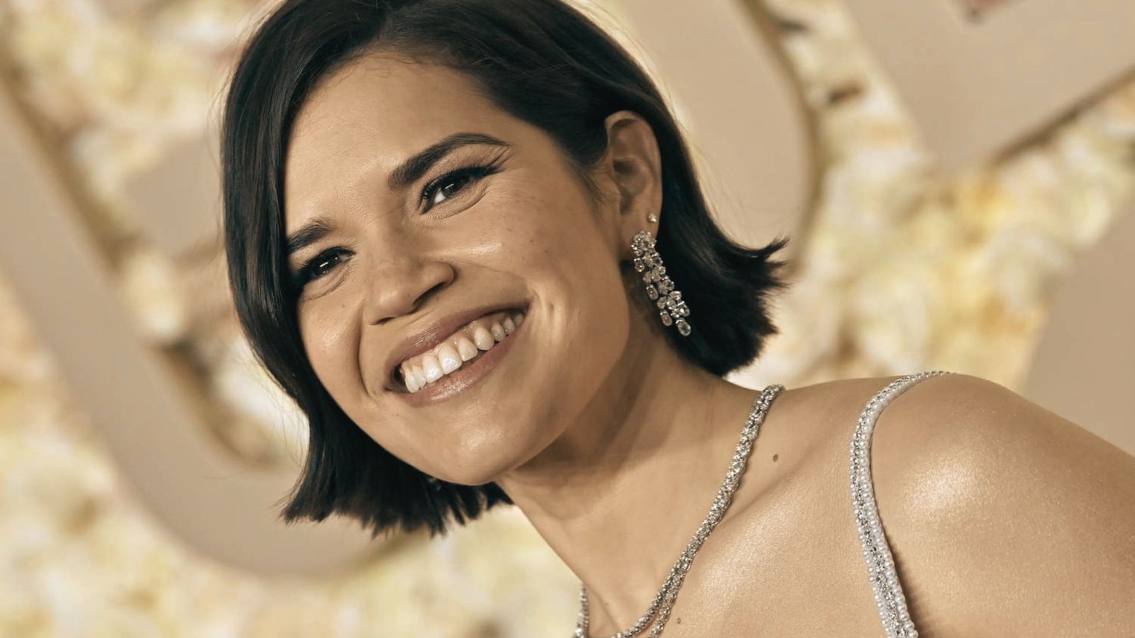 A woman with a retro flipped mullet hairstyle smiles warmly at the camera
