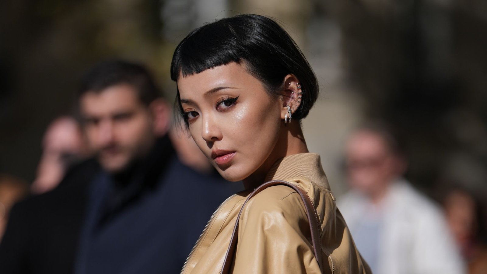 Woman with short black hair and straight micro bangs cut high above the eyebrows. The ultra-short blunt fringe creates a bold, graphic statement on a round face.