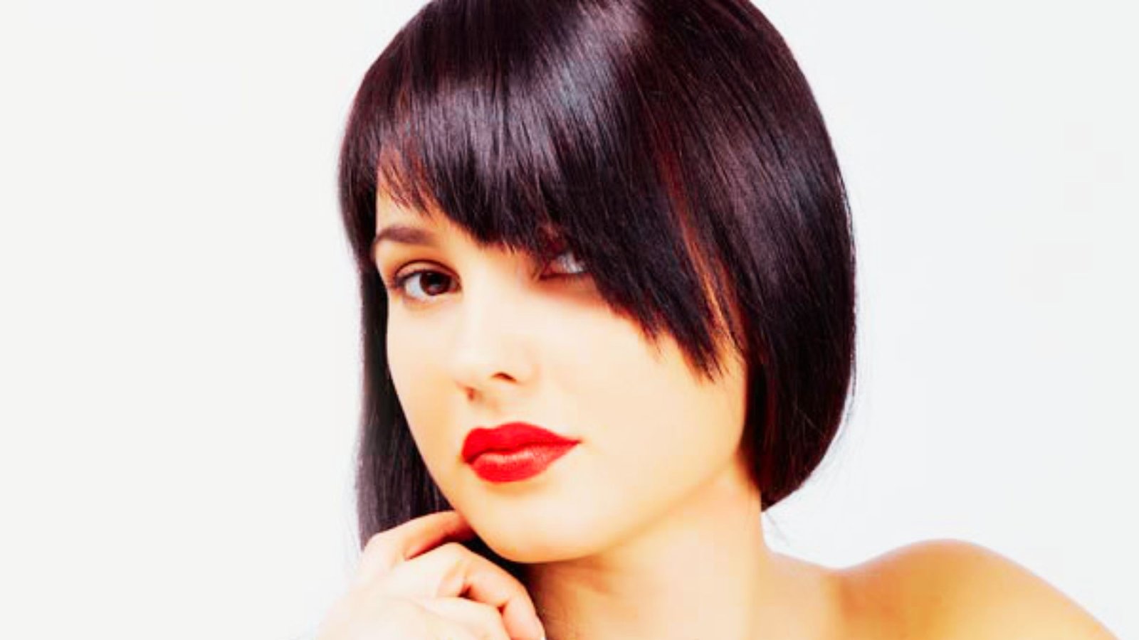  A woman with short hair and angled bangs, wearing bold red lipstick, showcasing a stylish and modern look.
