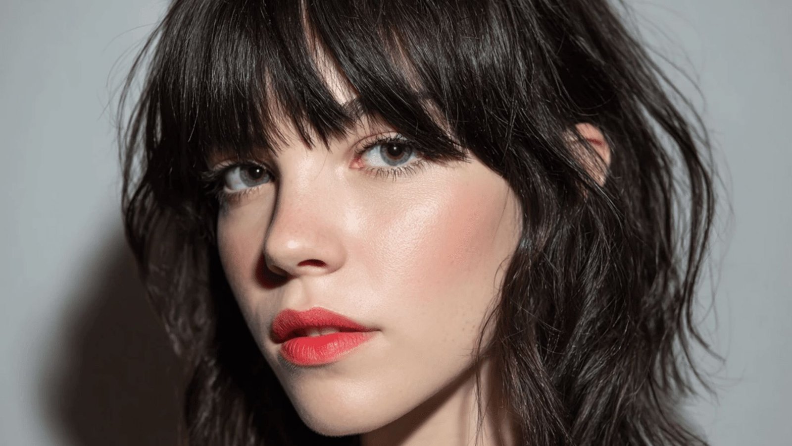 Close-up of woman with wavy brunette hair and wispy, textured bangs.
The piecey fringe is brow-skimming and softly blends into face-framing layers.