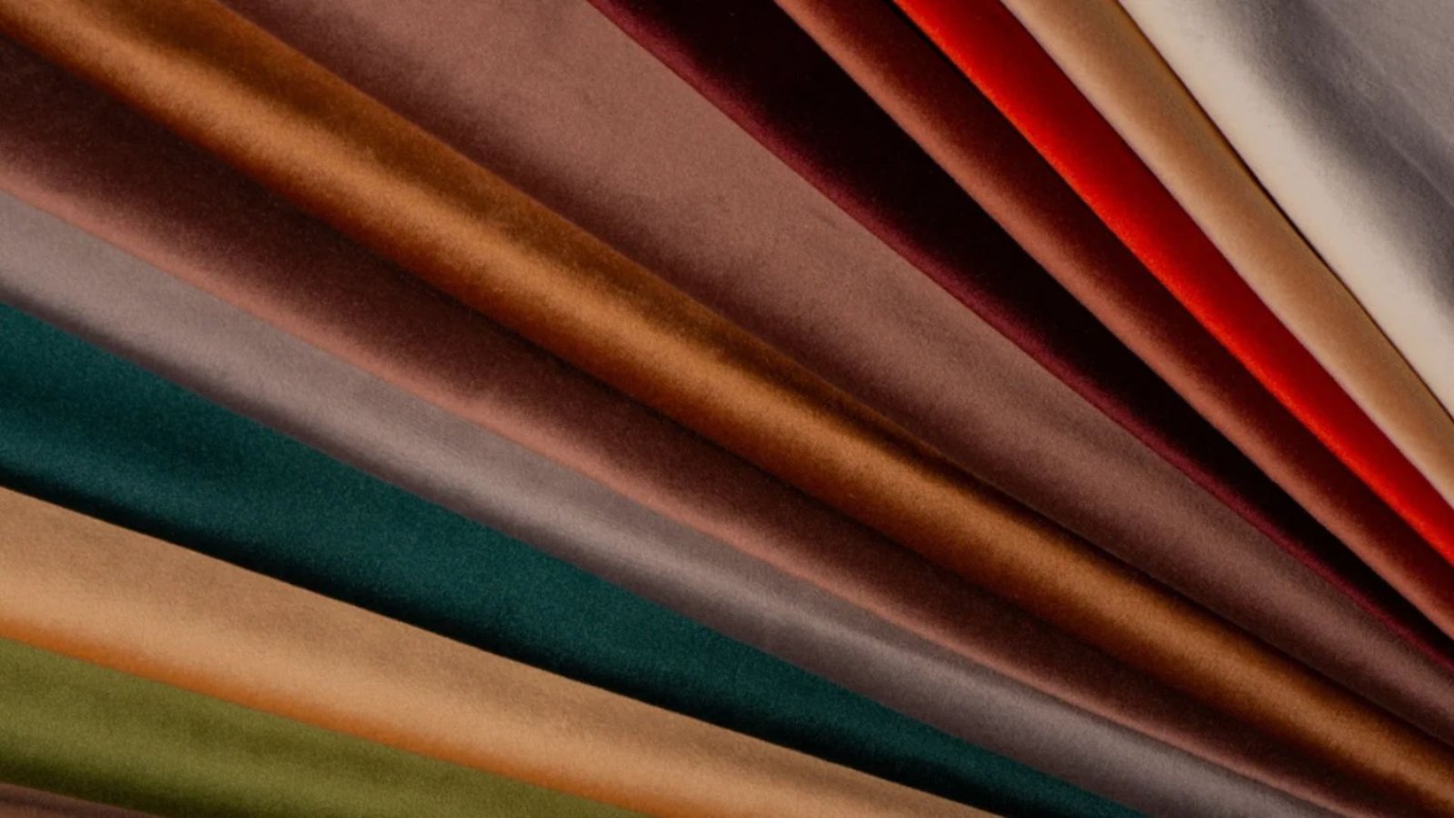 A fan of velvet fabric in rich colors—deep red, brown, green, blue, and tan. The soft textures and hues create a warm, luxurious feel.