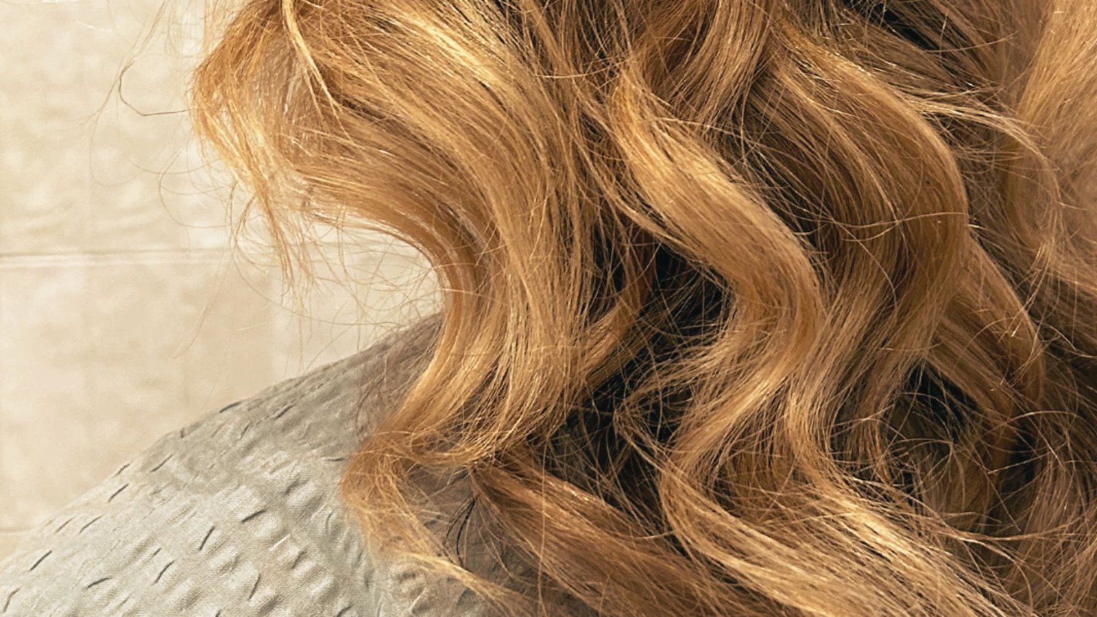 A woman with long, wavy hair stands in a bathroom, demonstrating a 'Dry Without Touching' hair care technique.