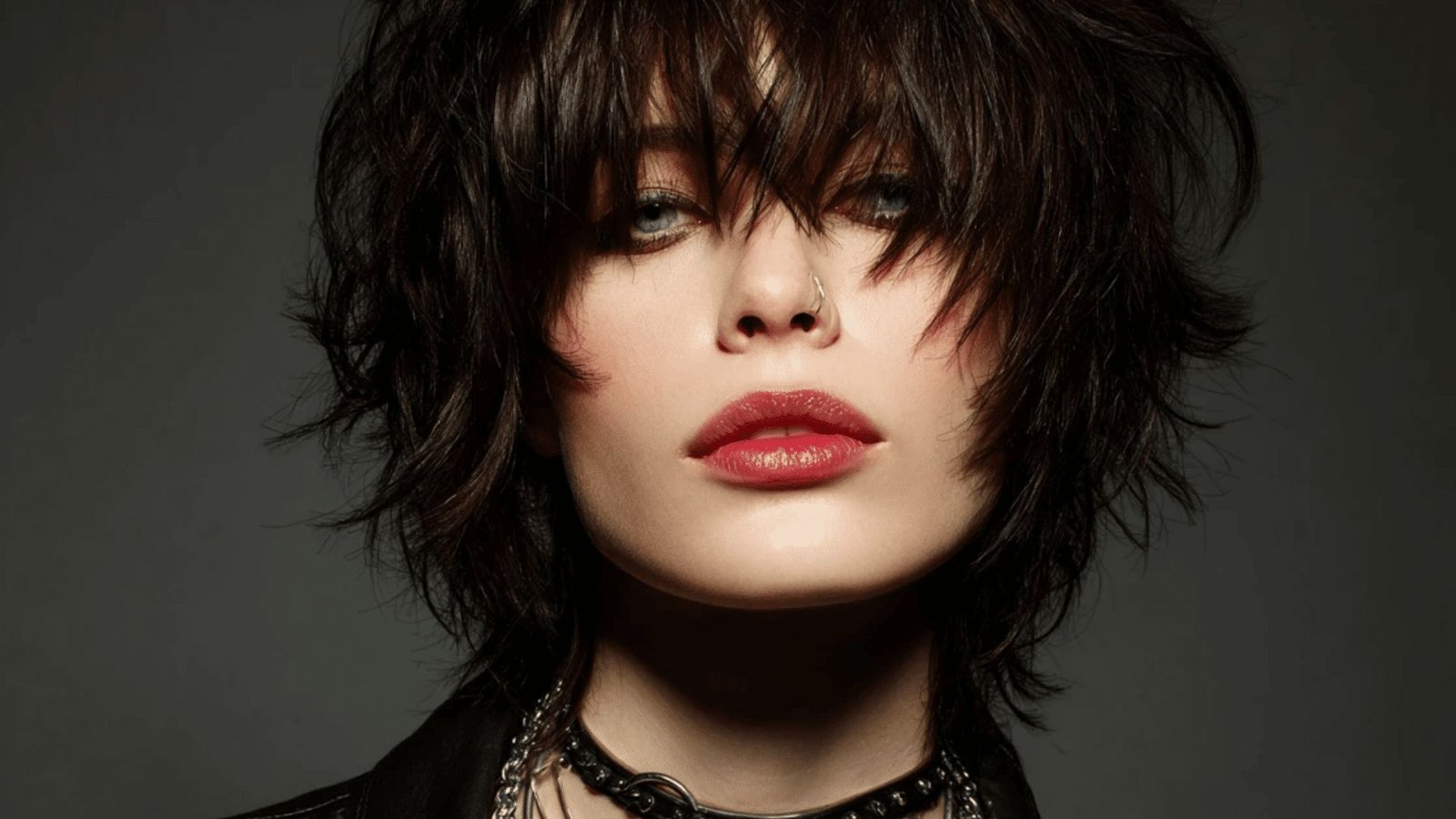 Woman with tousled dark brown shag and choppy, eyebrow-grazing bangs.
The textured, piecey fringe is cut unevenly for an effortless, rock-influenced look.