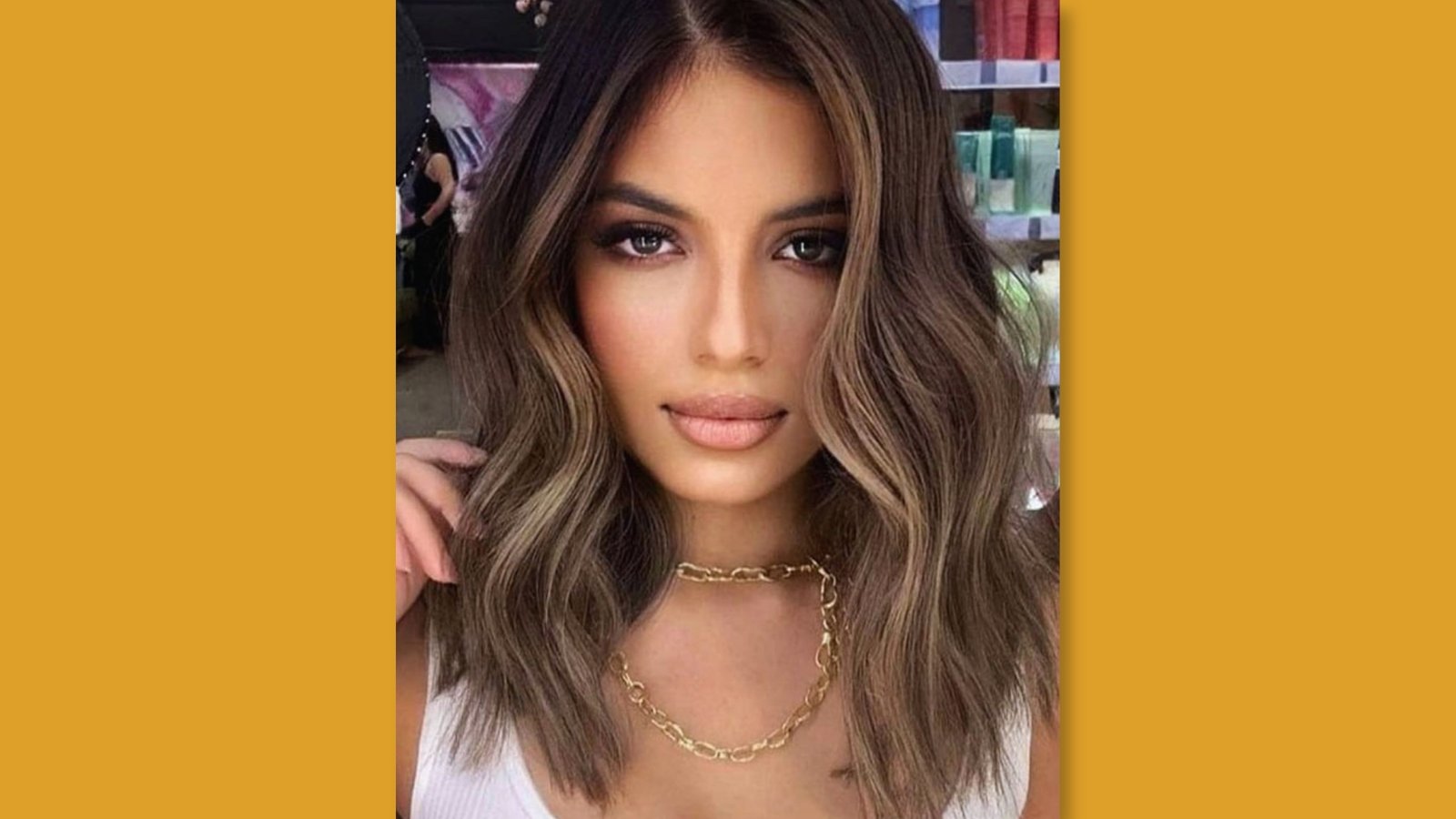Low maintenance wavy medium length layered lob with center part and dimensional balayage highlights on brown hair for round face 
