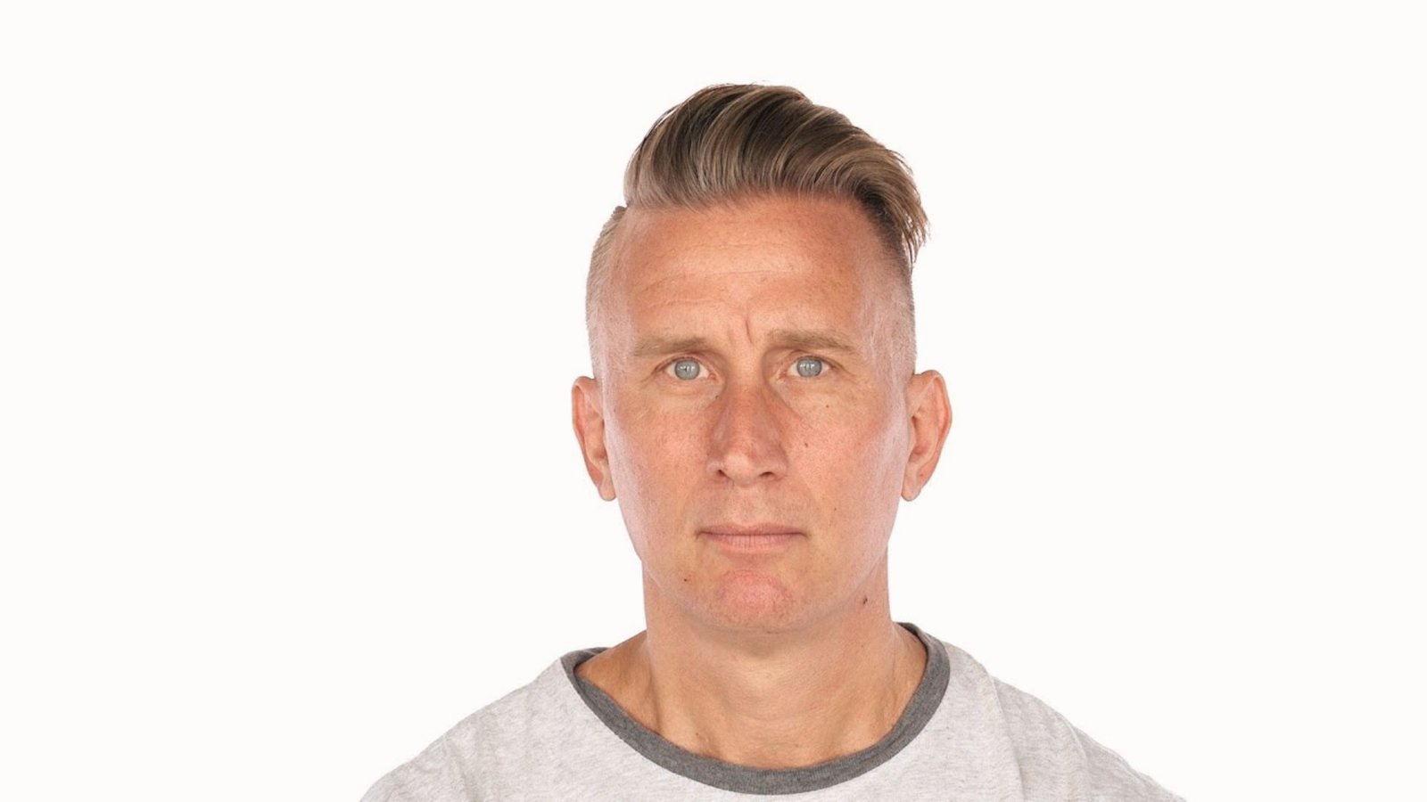 A man with a shaved head wearing a grey shirt, showcasing a hard part disconnected undercut fade hairstyle.