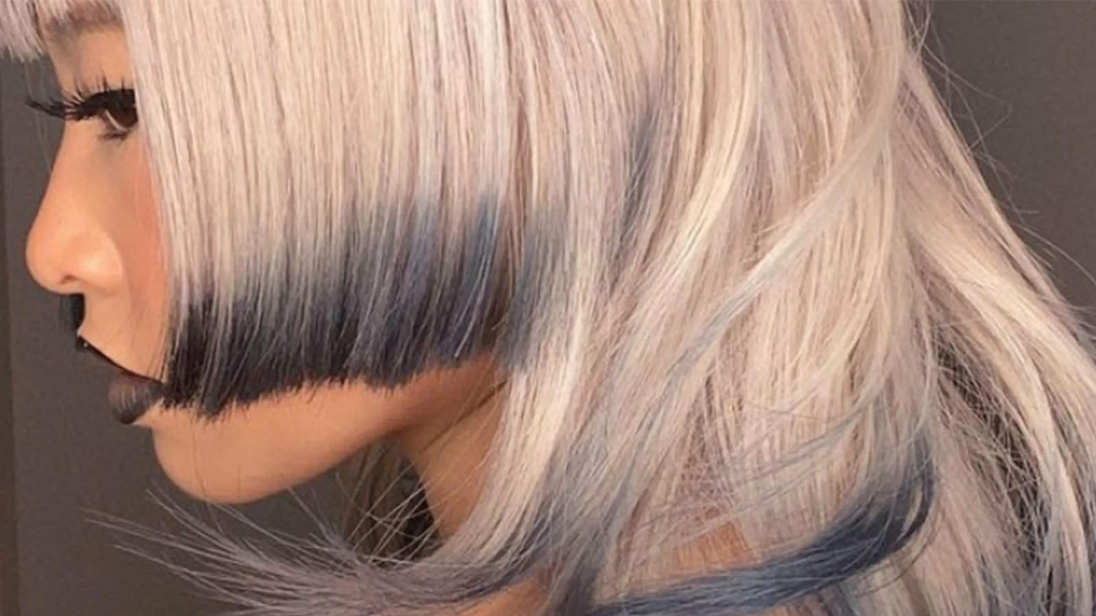A woman with long blonde hair featuring blue highlights styled in a Jellyfish Mullet.