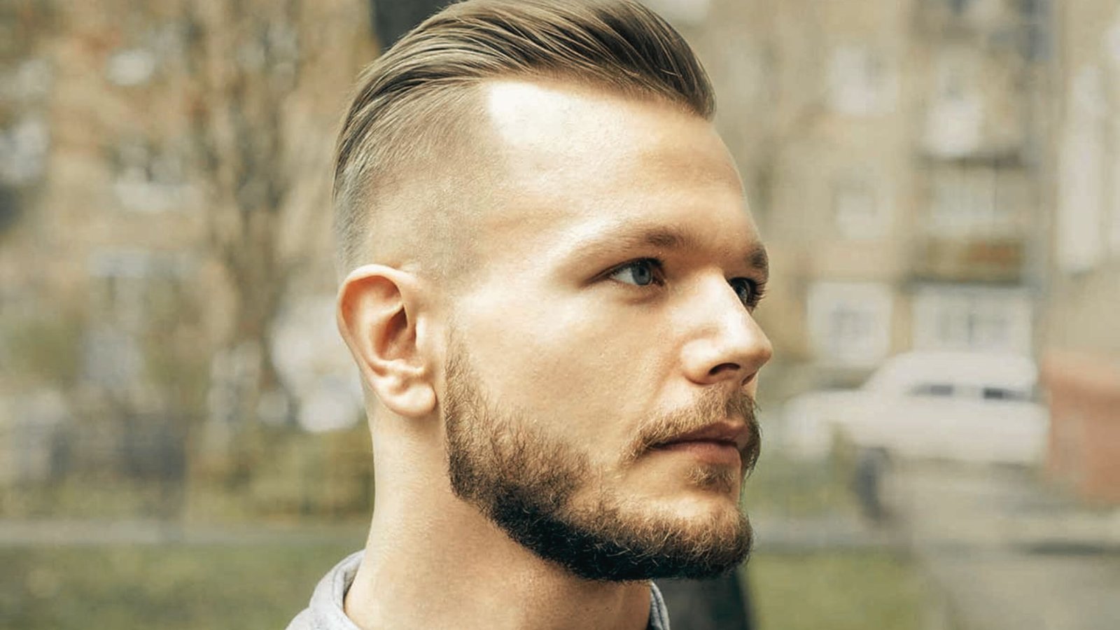 A man with a beard and short hair, showcasing a disconnected undercut fade hairstyle.