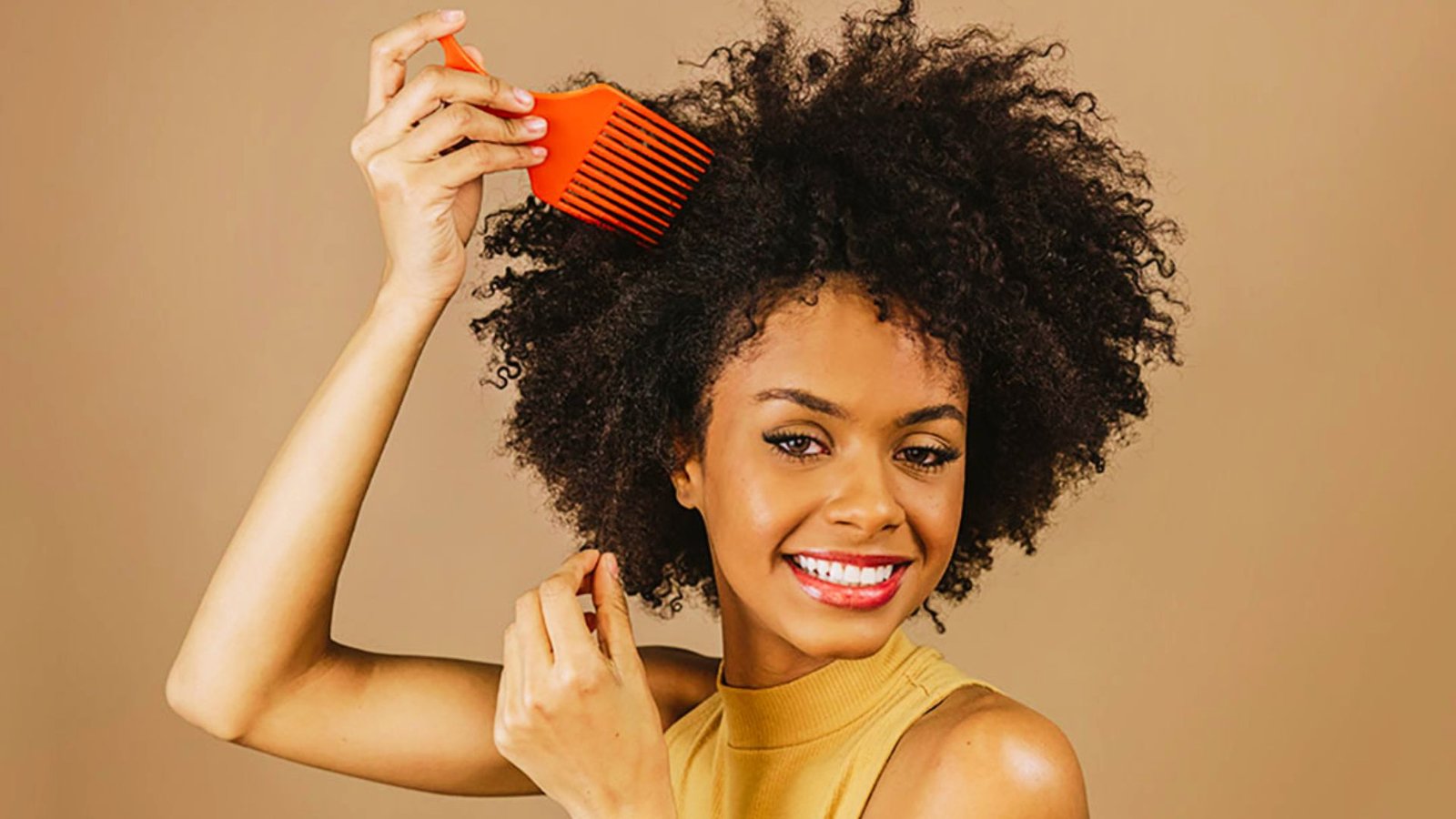 A woman with curly hair sections her hair while combing it, preparing for Senegalese twists.
