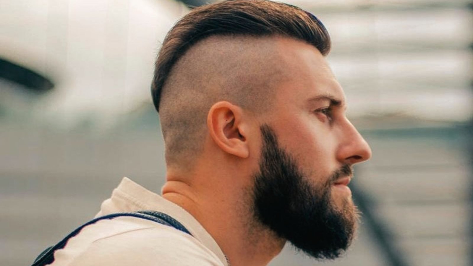 A man with a beard and a mohawk featuring a straight fringe and disconnected undercut fade.