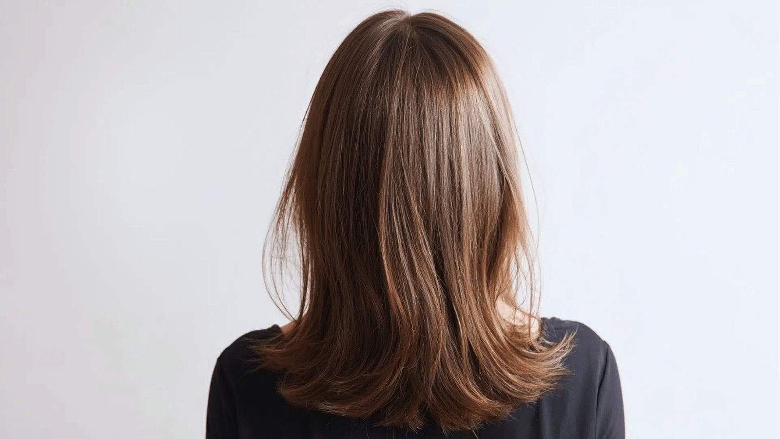 Back view of smooth straight shoulder length haircut with subtle layers on light brown hair