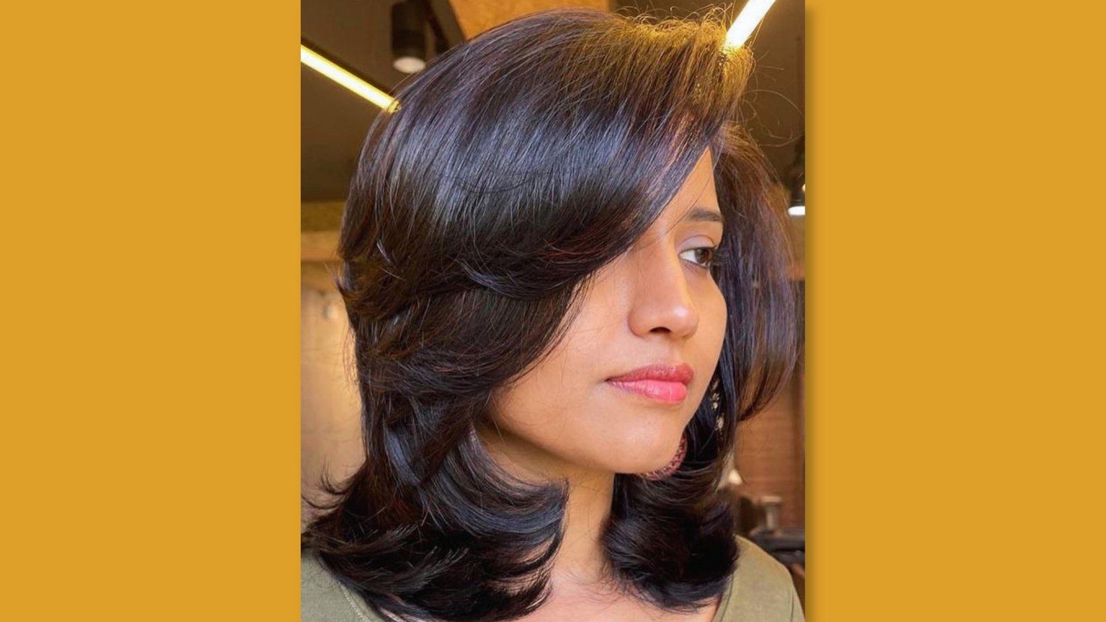 Low maintenance layered medium length haircut with voluminous side-swept bangs and soft face-framing layers on glossy dark brown hair for round face 
