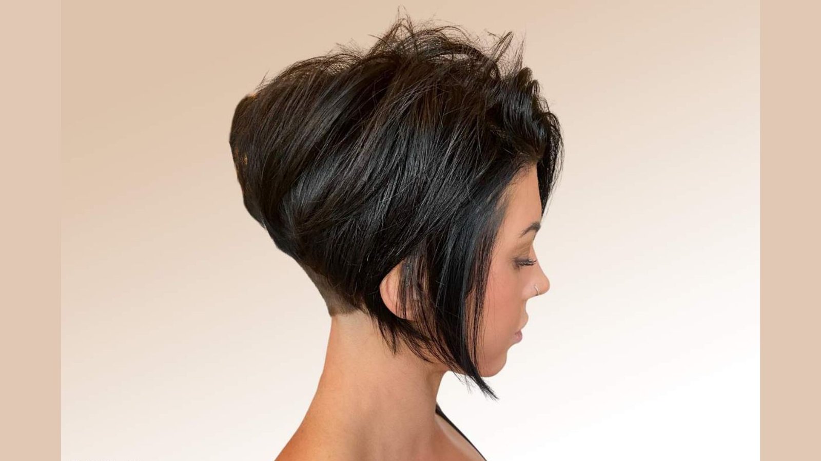 Side profile of a woman with a voluminous black stacked bob and undercut at the nape.