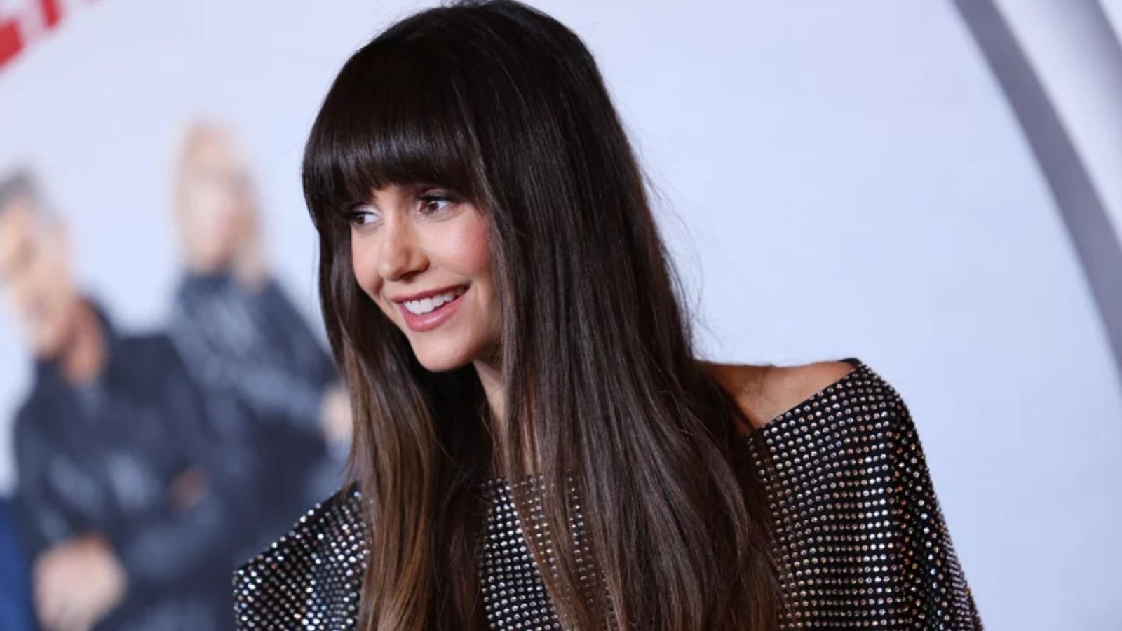 Woman with long, straight dark brown hair and thick, blunt bangs cut straight across forehead. The bangs are heavy and end just above the eyebrows.