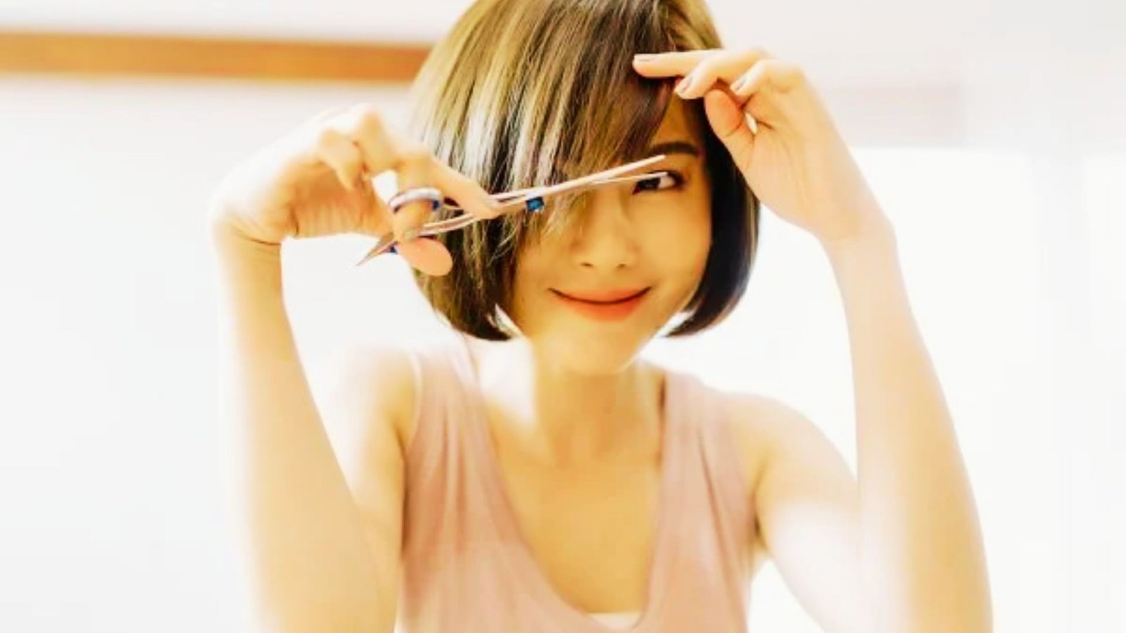 A woman creating the Bardot Bangs Shape
