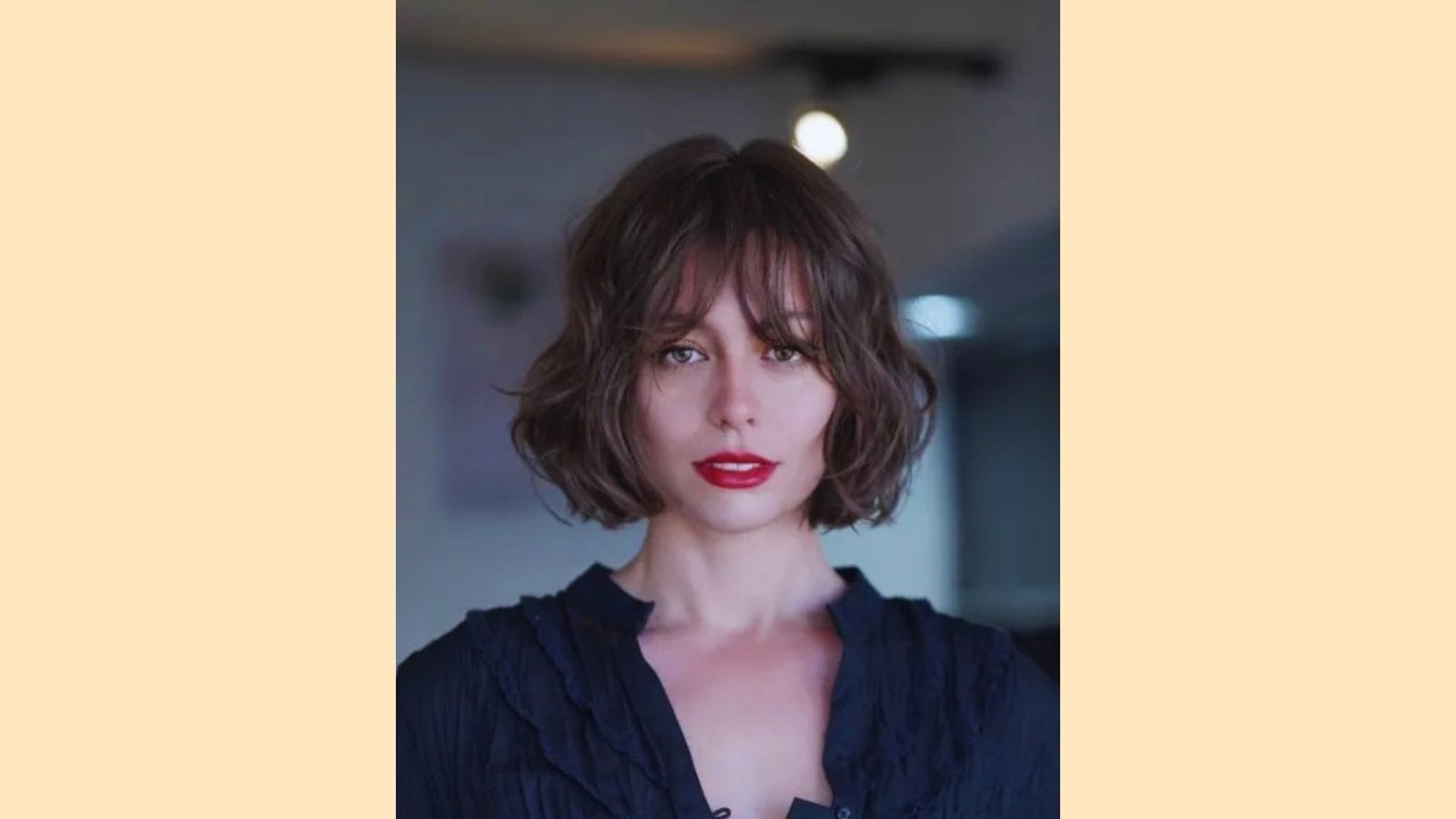 Wavy brunette French bob with piecey curtain bangs and tousled chin-length texture