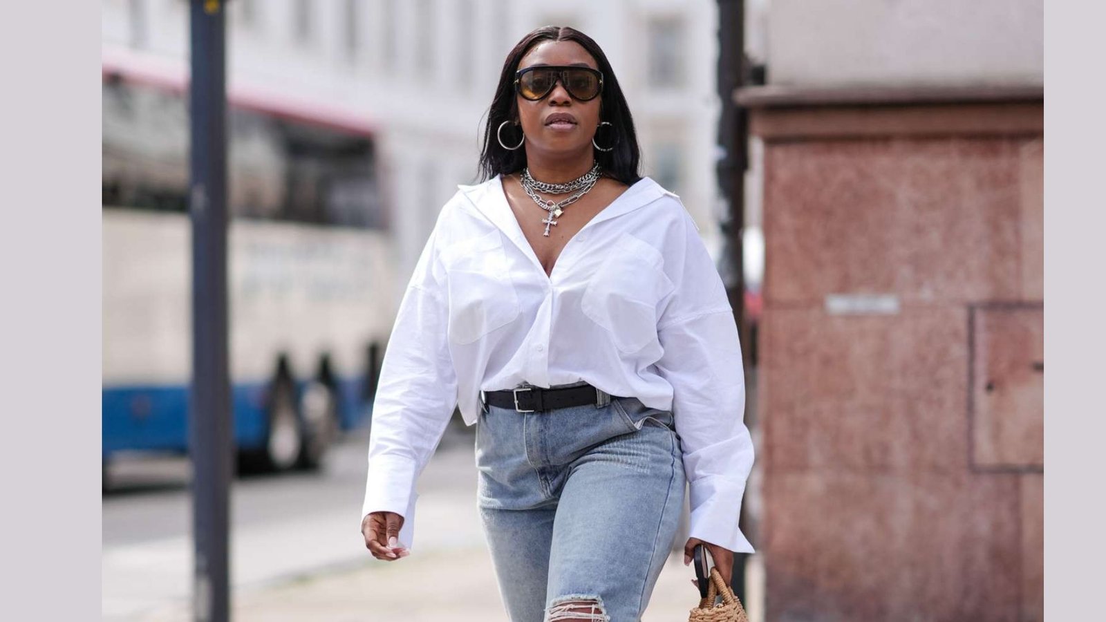 Confident plus-size mom outfit with oversized white shirt and ripped jeans. Layered necklaces and hoops for an effortless street style look.
