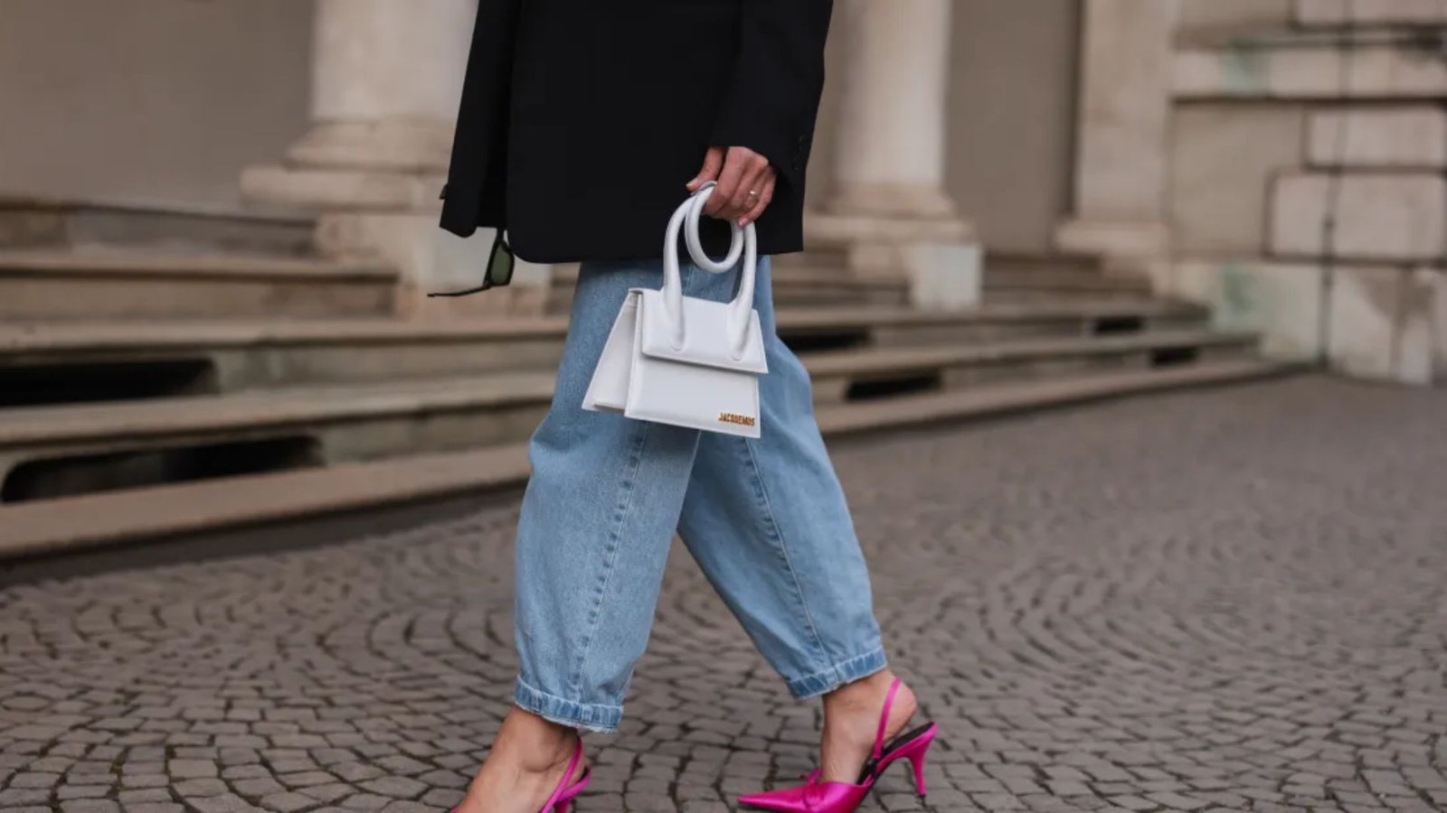 90s mom outfit with cuffed mom jeans, hot pink slingback heels, and black blazer. A structured white mini handbag completes the look on cobblestone.