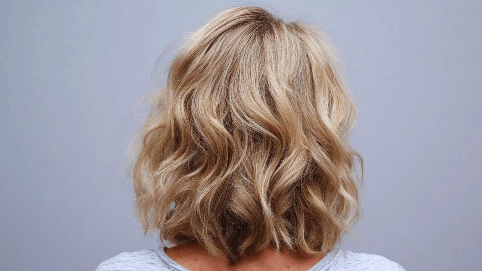 Back view of tousled wavy shoulder length haircut with textured layers on dimensional blonde hair