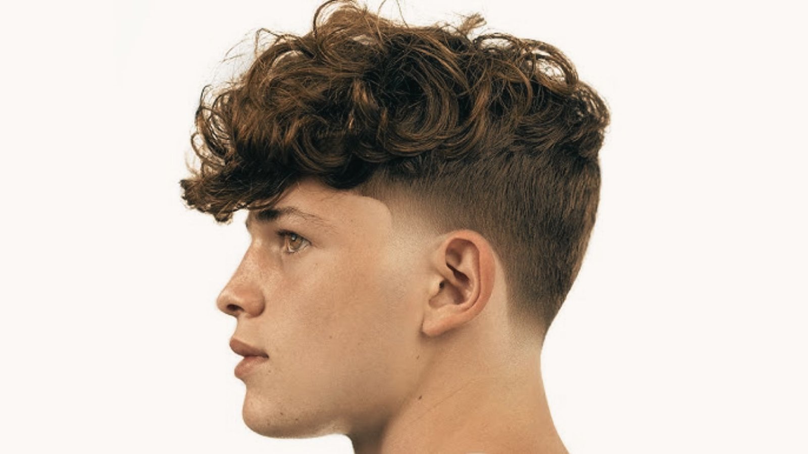 A young man with a curly disconnected undercut fade hairstyle, showcasing his textured curls and stylish cut.
